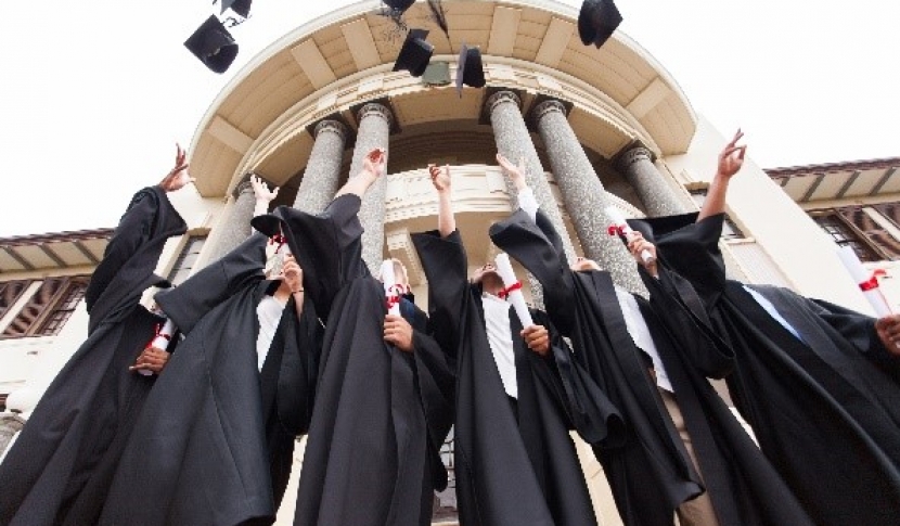 Students tossing graduation caps in air