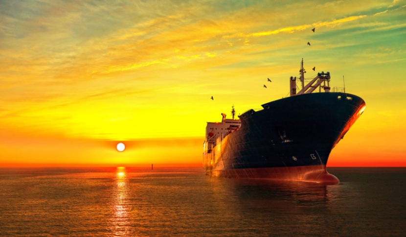 Large ship on the ocean with the sunsetting behind it