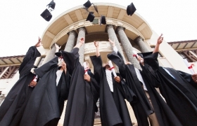 Students tossing graduation caps in air